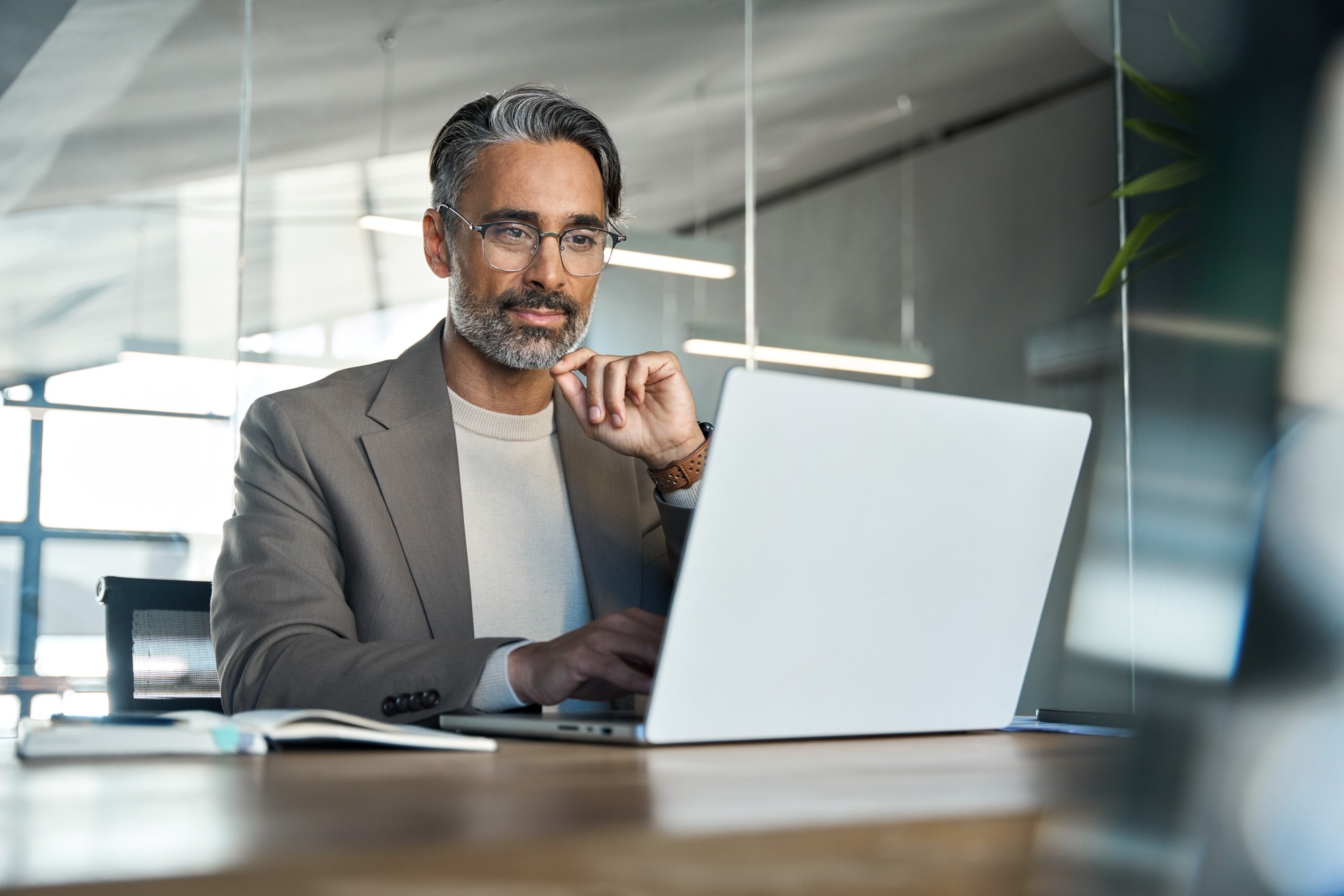 Business professional engaged in work at a laptop in a modern office setting, reflecting focus and concentration. Ideal for productivity topics.